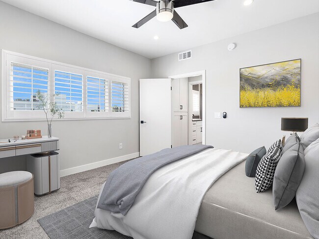 Carpeted bedroom with ceiling fan and large windows for natural light.