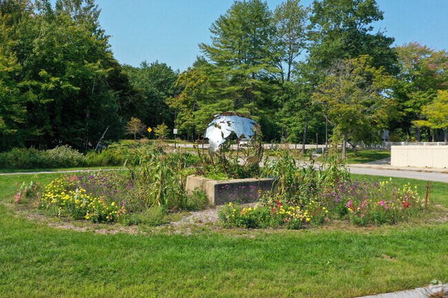 A globe sculpture surrounded by a lush garden at Casco Bay High School in North Deering.