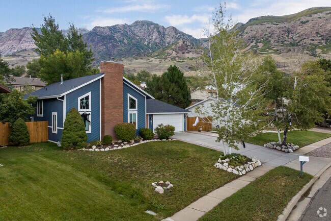 A gorgeous navy blue home with red brick sits in the mountains.