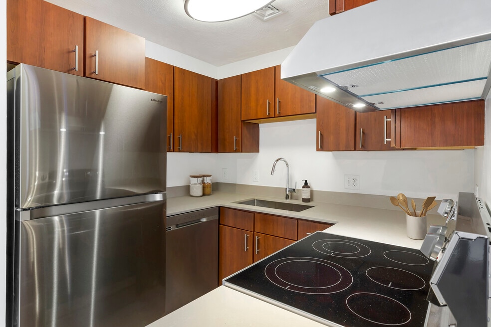 Renovated Package III kitchen with stainless steel appliances, grey quartz countertops, white or cherry cabinetry, and hard surface flooring