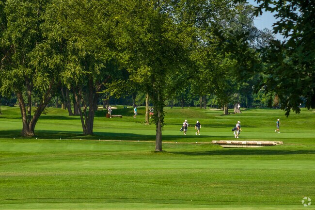A group of River Grove residents walk along the green of a golf course.