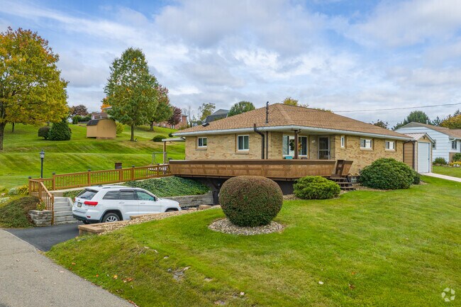 A brick ranch-style home with a wrap-around deck sits on lightly rolling hills in Daugherty Township.