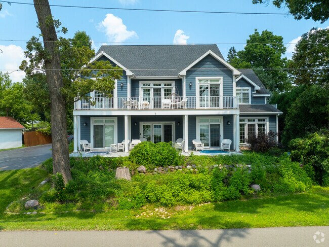 A two-story vacation home in Como, Wisconsin, showcases blue siding and a spacious wraparound porch.
