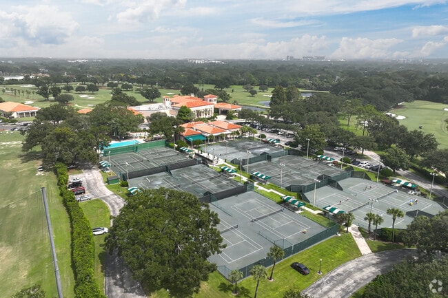 A stunning aerial perspective highlights the MetroWest Golf Club tennis courts framed by the lakefront setting.