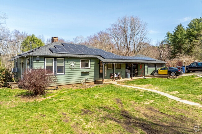 A green clapboard sided ranch style home in Chaplin has solar panels and mellow earth tones.
