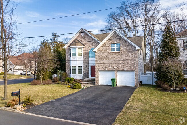 A ground view of a Colonial with tall, arched entryway from the right in Edison, NJ.
