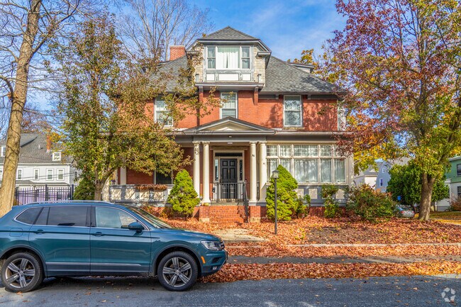 A brick single-family home in Institution Park has a leaf-covered lawn and ample shade.