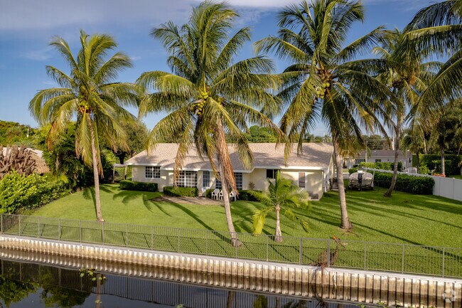 Palm trees adorn this waterfront Ranch style home in Lake Clarke Shores, FL.