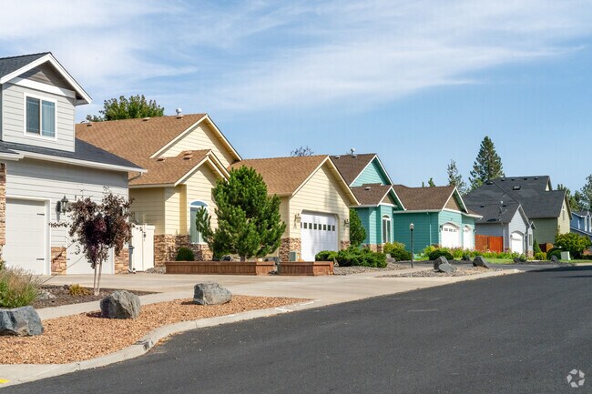 Charming Larkspur homes line the street, each with unique character and vibrant gardens.