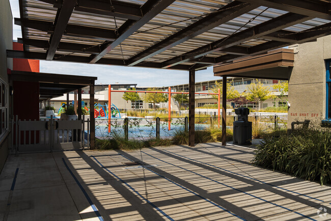 Playground lot and open field for kids to explore during recess with shade.