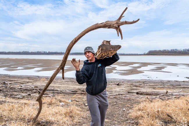 A man tosses driftwood in the air to get a better grip at North Riverfront Park near Riverview.