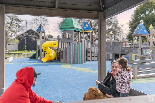 A family huddles underneath a covered seating area at Matteo's Playground.