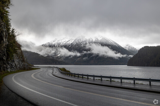 Scenic Sawmill Creek Road curves past snowy peaks and misty coastline in Sitka, Alaska.