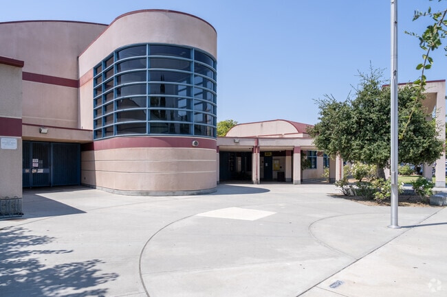 The school’s front entrance is framed by palm trees and a neatly maintained lawn, creating a warm and inviting atmosphere.