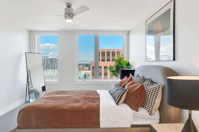Bright and airy bedroom with a modern aesthetic, showcasing floor-to-ceiling windows with a stunning city view, stylish decor, and plush bedding for a cozy, inviting atmosphere.