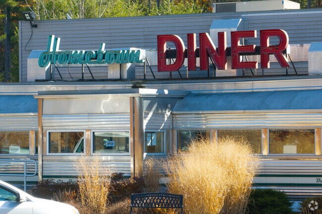 The classic chrome exterior and retro neon sign of the Hometown Diner in Rindge, New Hampshire, glowing under the bright autumn sun.