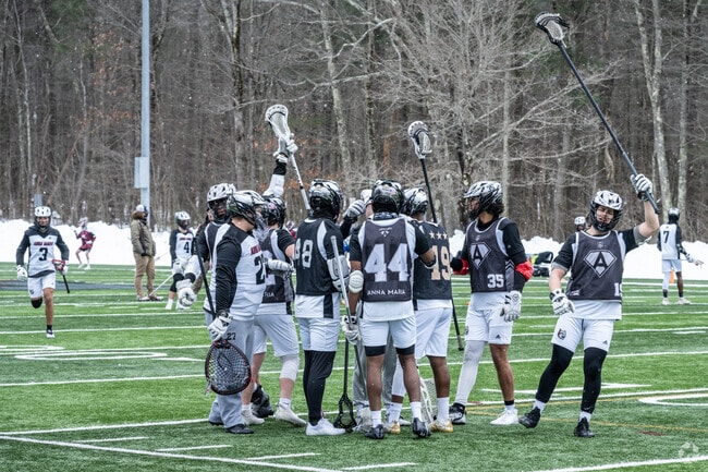 Anna Maria College lacrosse players celebrate the start of a game in Paxton.