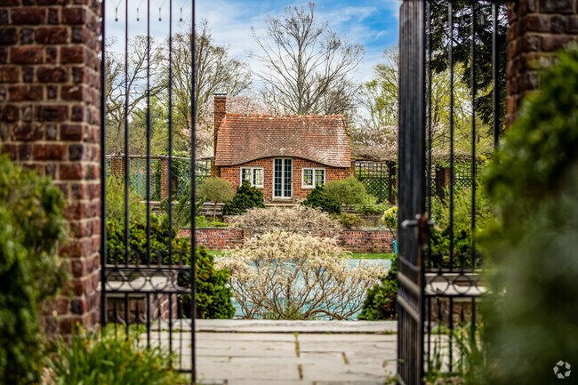 An open gate frames a view of the gardens at Planting Fields Arboretum.