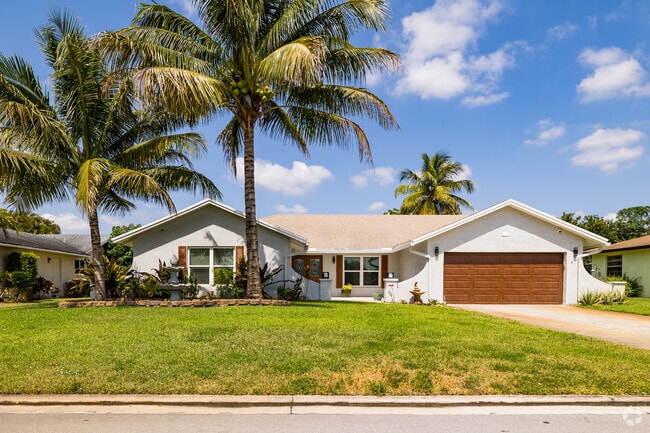 Village Walk ranch home shaded by palm trees.