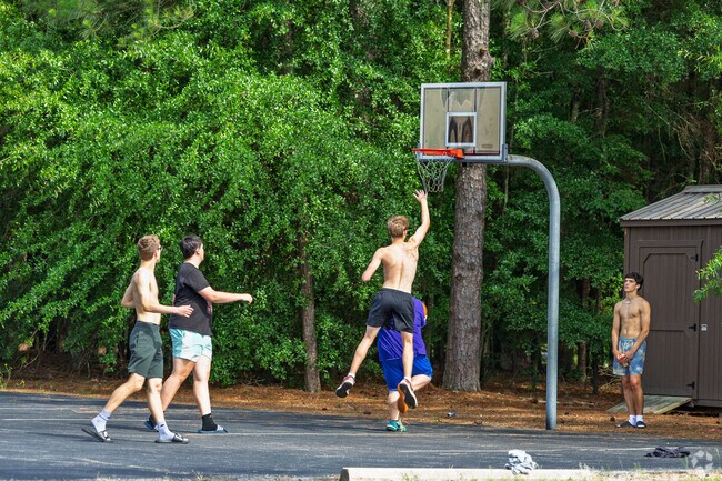 Teens play basketball at Rassie Wicker Park in Pinehurst during a sunny afternoon.