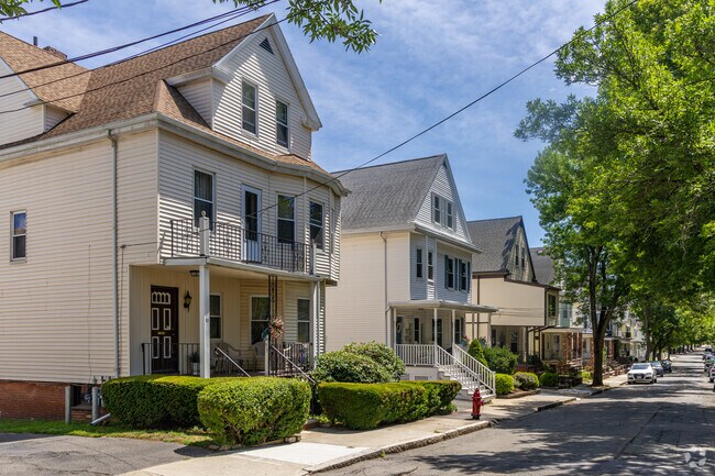 A row of multifamily homes along a tree-lined street in Teele Square, Somerville.