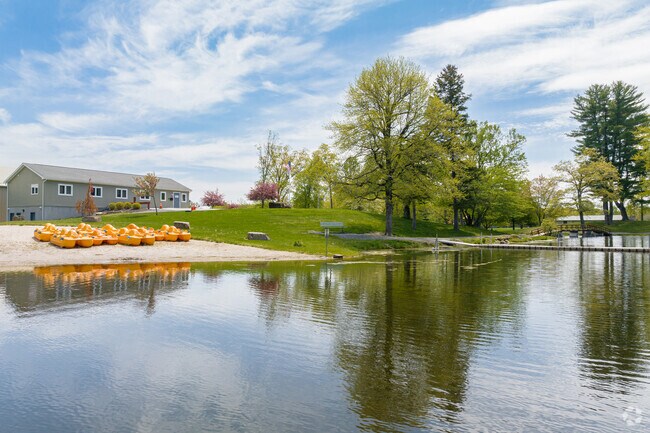 Scenic view of Circleville Park featuring a calm lake, paddle boats on the sandy shore, and lush greenery.