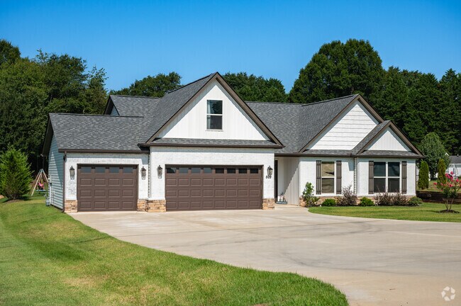 A white craftsman style house with a large front yard.