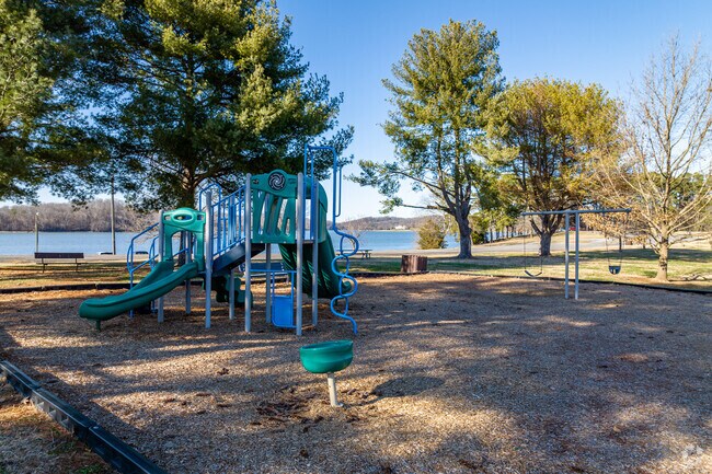 The Louisville Point Park's playground is shaded by the surrounding trees.