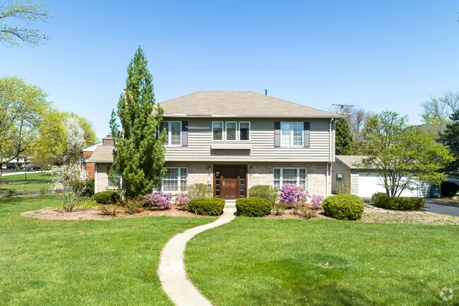 Colonial style home in neutral color scheme and slightly curved entrance path in Ridgewood.