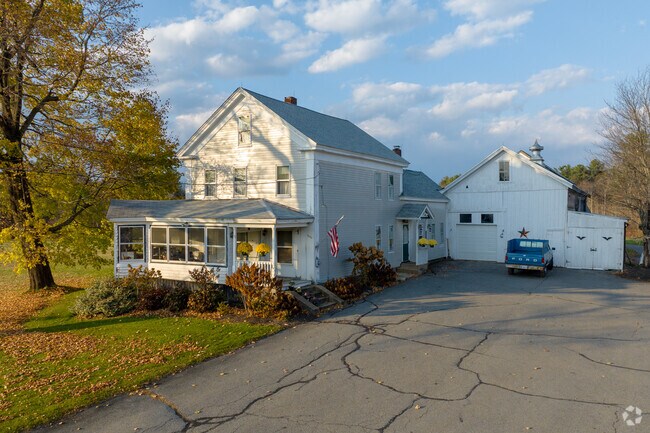 A farmhouse colonial in Leicester has a large driveway and attached barn.