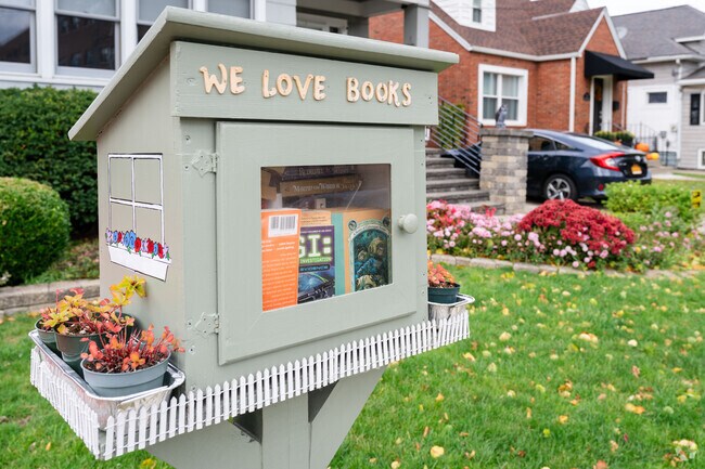 This free little library in Abbott McKinley has a variety of books and a white fence.