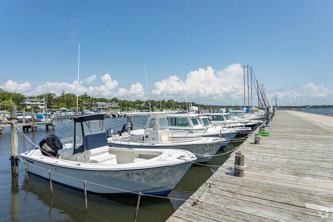 Bellport Village marina with boats docked along a scenic waterfront pier, offering easy access to the bay and a vibrant boating community.