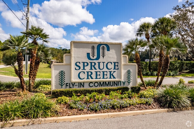 The entrance sign to Samsula-Spruce Creek surround by palm trees.