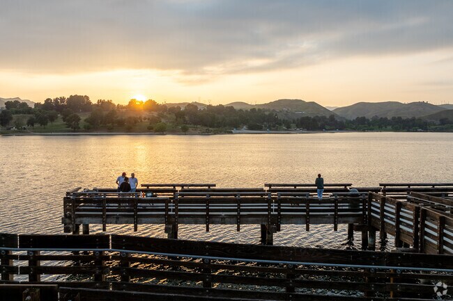 People fish at Castaic Lake while the sun sets over the mountains.