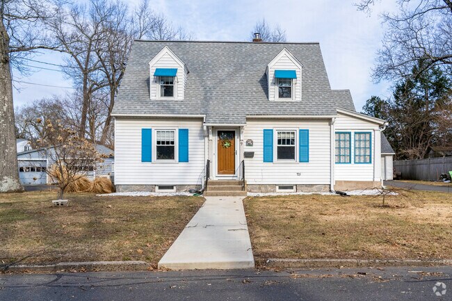 A cape style home in Thompsonville has contrasting blue shutters with white vinyl siding.