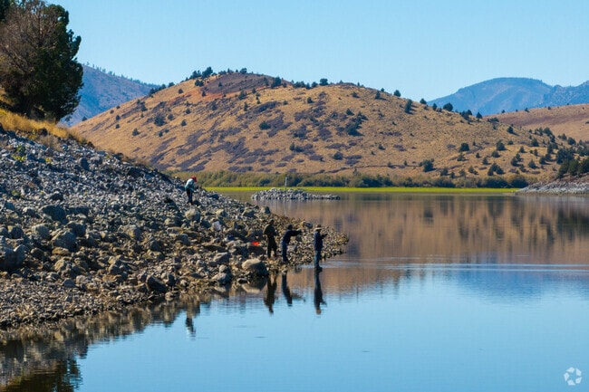 Anglers fish from Lake Shastina’s rocky shoreline with views of rolling hills.