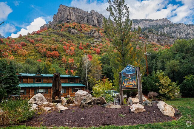 A bear carved of wood and an artistically carved wood sign stand in front of the Alaskan Inn and
