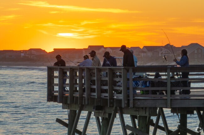 Golden skies and peaceful waters as the sun sets on the Surf City Pier.