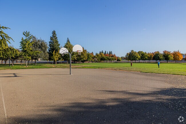 A father and son play football beside Freedom Park's basketball court.