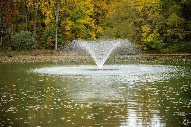 Autumn colors surround a peaceful lake with a fountain in Milford.