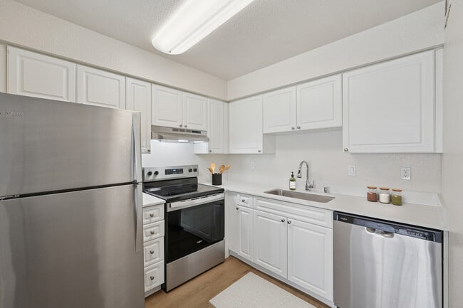 Classic II Collection kitchen with stainless steel appliances, white cabinetry, quartz countertops, and hard surface flooring