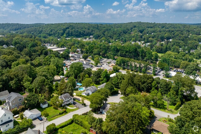 An aerial view shows rural Bedford Hills, NY, populated with dense, mature trees.