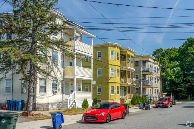 A row of triple decker multifamily homes in South Common are painted in a variety of colors.