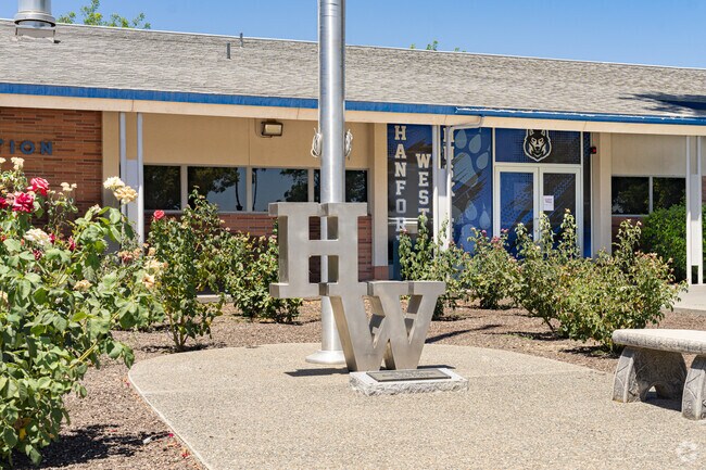A large metal H and W anchor the flag pole outside the entrance to Hanford West High School.