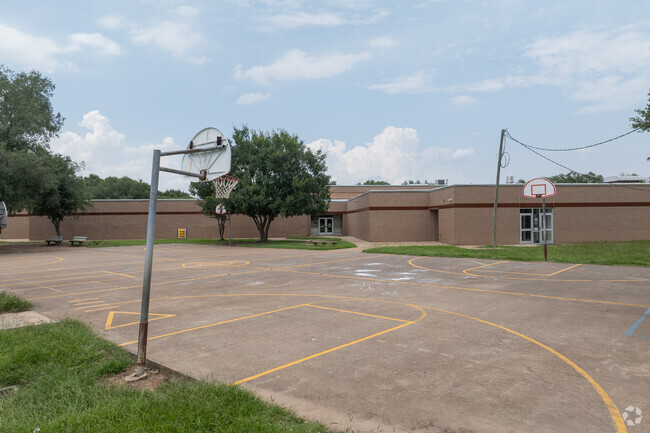 Students enjoy a colorful playground and a basketball court for recreation.