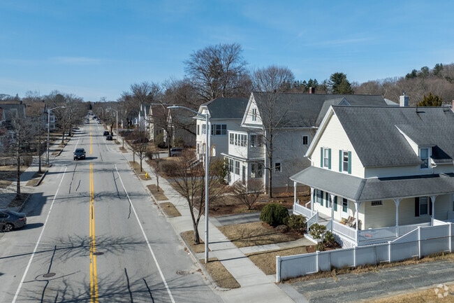 A peaceful suburban street lined with charming, shingle-style homes and bare winter trees on a bright day in Newton Square.