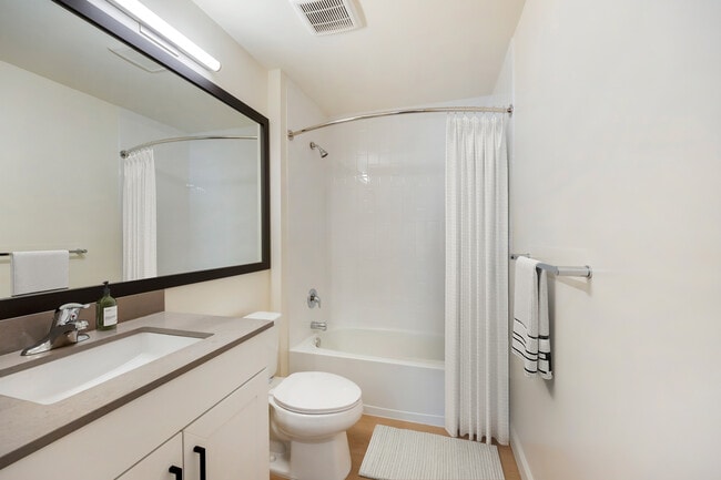 New Apartments bath with grey quartz countertop, white cabinetry, and hard surface flooring
