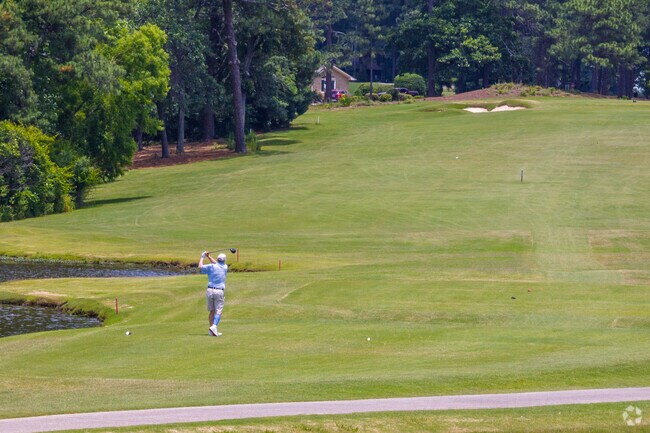 A golfer tees off near the water at one of Pinehurst’s iconic championship golf courses.