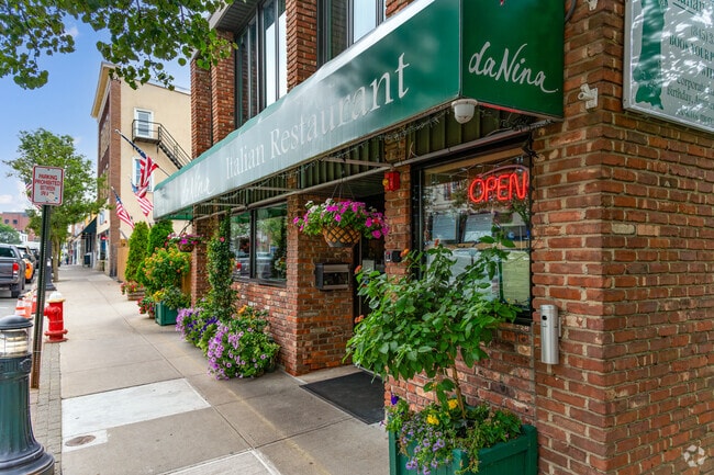 Da Nina Italian Restaurant in Suffern welcomes guests with a green awning, brick facade and vibrant floral decor.