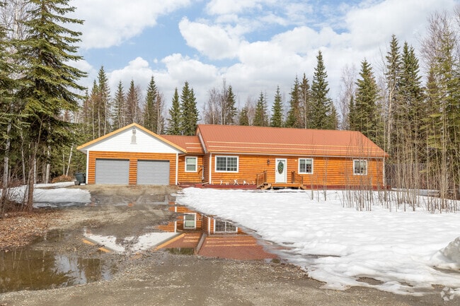 A vibrant orange ranch home reflects in a thawing puddle in Badger.